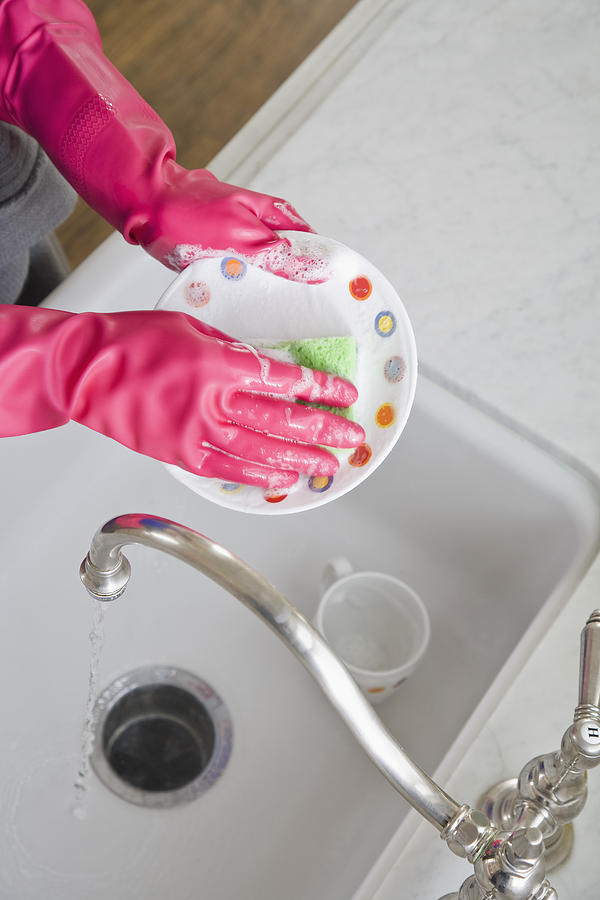Person washing dishes in kitchen sink Photograph by Jupiterimages