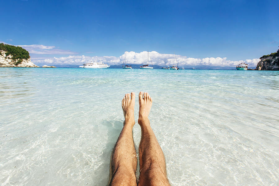 Personal perspective of mans feet in clear turquoise water Photograph by Alexander Spatari
