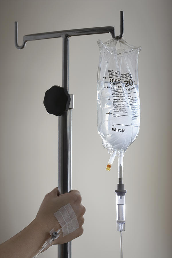 Persons hand holding stand with drip bag Photograph by Moodboard