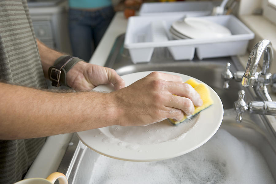 Persons hands washing dishes Photograph by Pixland