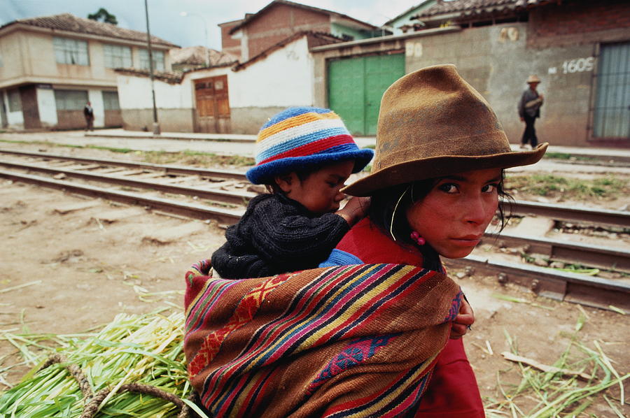 Peru,Cuzco,Quechua Indian girl with sibling on back,selling leeks Photograph by Jeremy Horner