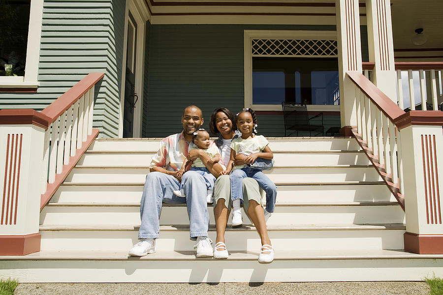 Photo of a young family sitting on the steps in front of their house. Photograph by Justin Horrocks