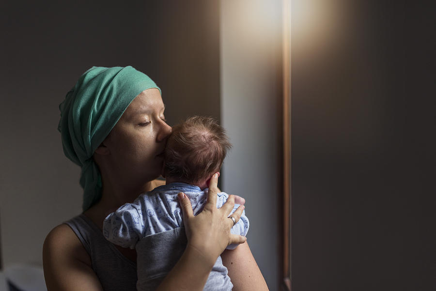 Photo of Female cancer patient holding her baby son next to the window Photograph by Ljubaphoto