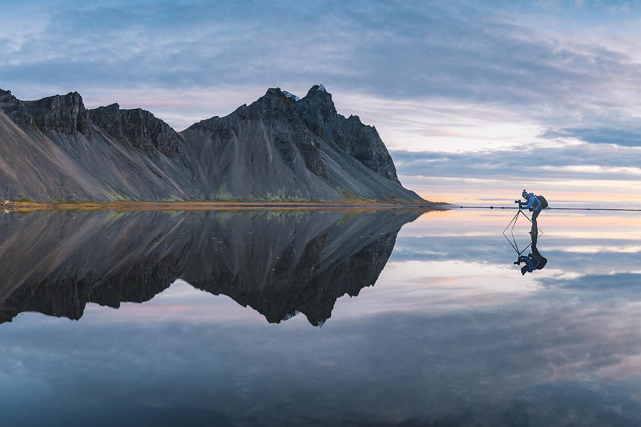 Photographer standing on a mirroring layer of water, Iceland Photograph by © Marco Bottigelli