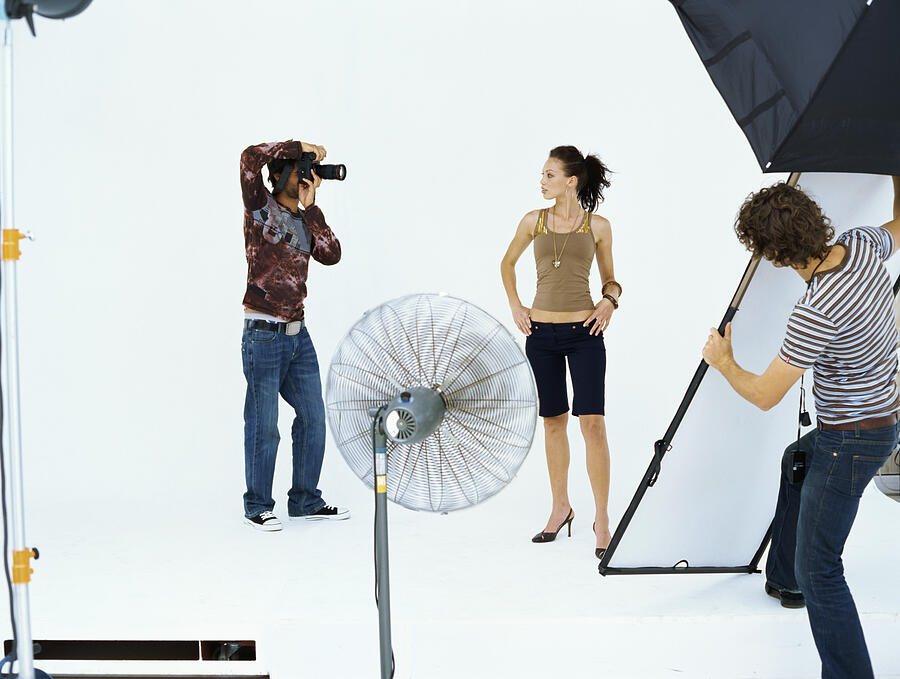 Photographer taking a photograph of a young woman in a studio Photograph by Stockbyte