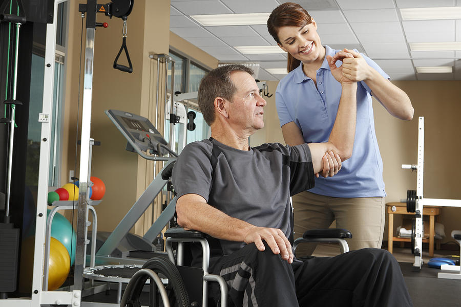 Physical therapist evaluating range of motion of patient in wheelchair Photograph by Dny59