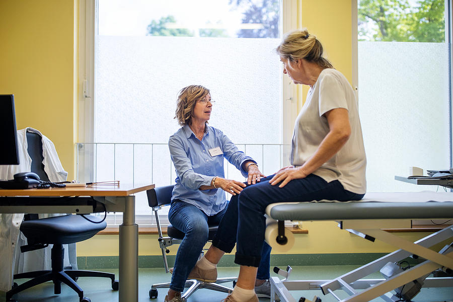 Physiotherapist checking knee of female patient stock Photograph by Luis Alvarez