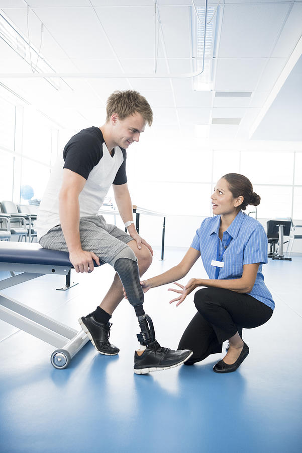 Physiotherapist explaining to young man with prosthetic leg Photograph by JohnnyGreig