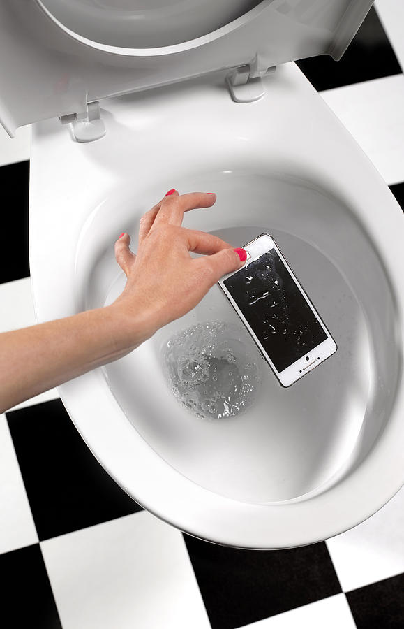 Picking smart phone out of toilet Photograph by Peter Dazeley