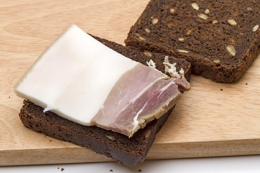 Piece of salty bacon on rye bread Photograph by Ra3rn