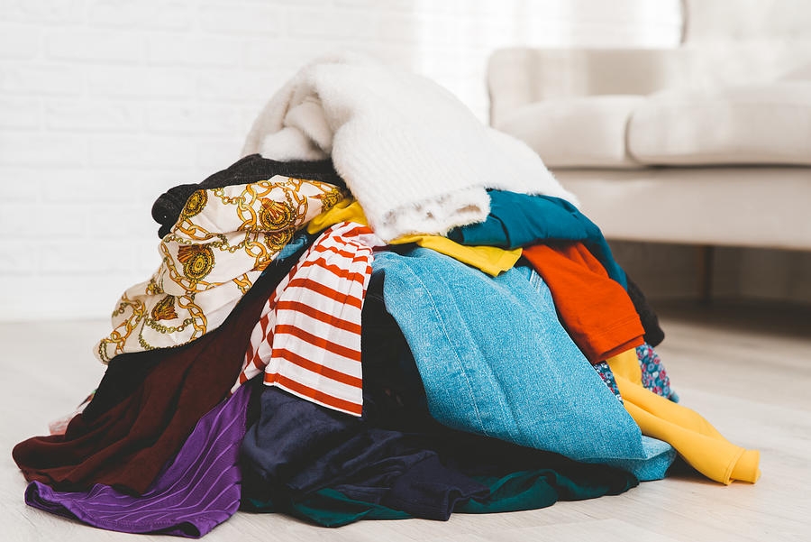 Pile of unfolded clothes for laundry on the floor. Heap of used clothes for donation or recycling. Decluttering concept Photograph by Damian Lugowski