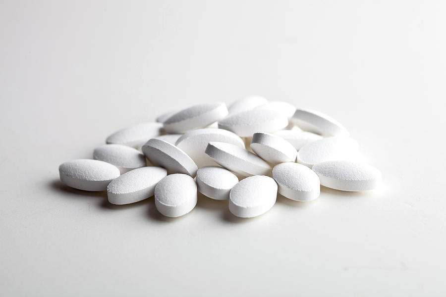 Pile of white drug pills laying on white background. Medical con ...