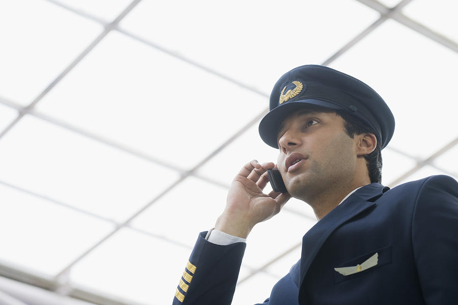 Pilot talking on a mobile phone at an airport Photograph by Photosindia
