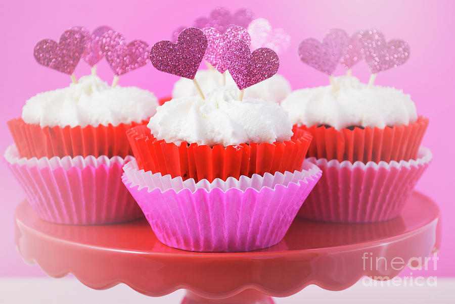 Pink and white cupcakes with heart shape toppers.  Photograph by Milleflore Images
