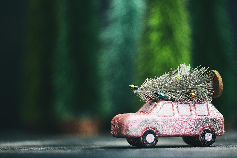 Pink car transporting Christmas tree. Christmas holiday background. Photograph by CatLane