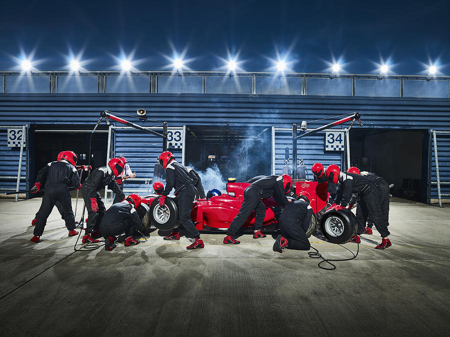 Pit crew working on formula one race car in pit stop Photograph by Caia Image