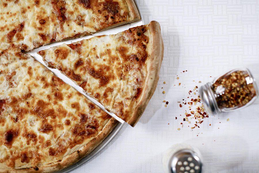 Pizza slice with spilled chili flakes Photograph by Image Source RF/Chad Springer