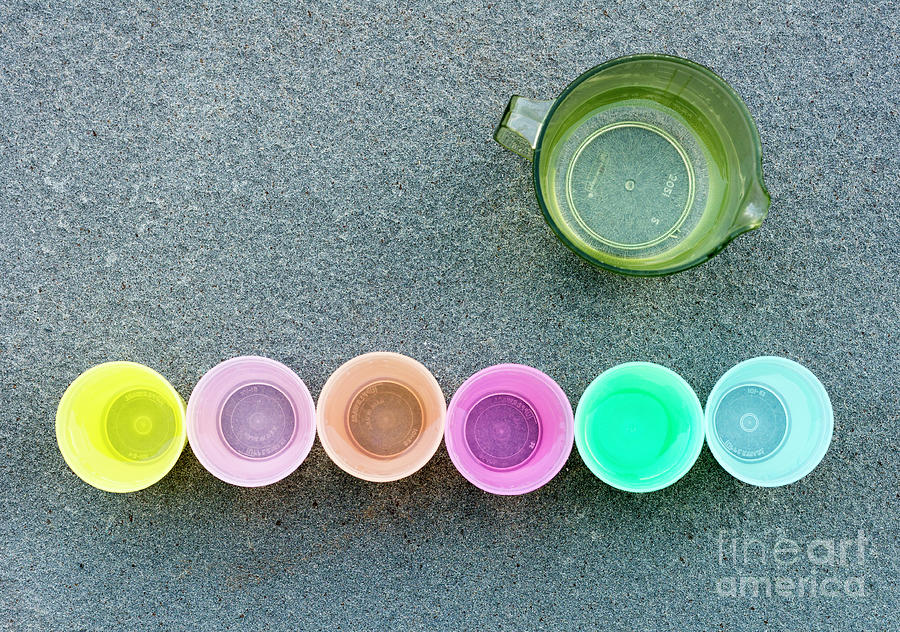 Plastic cups lined up on a stone slab for a childs tea party Photograph by William Kuta