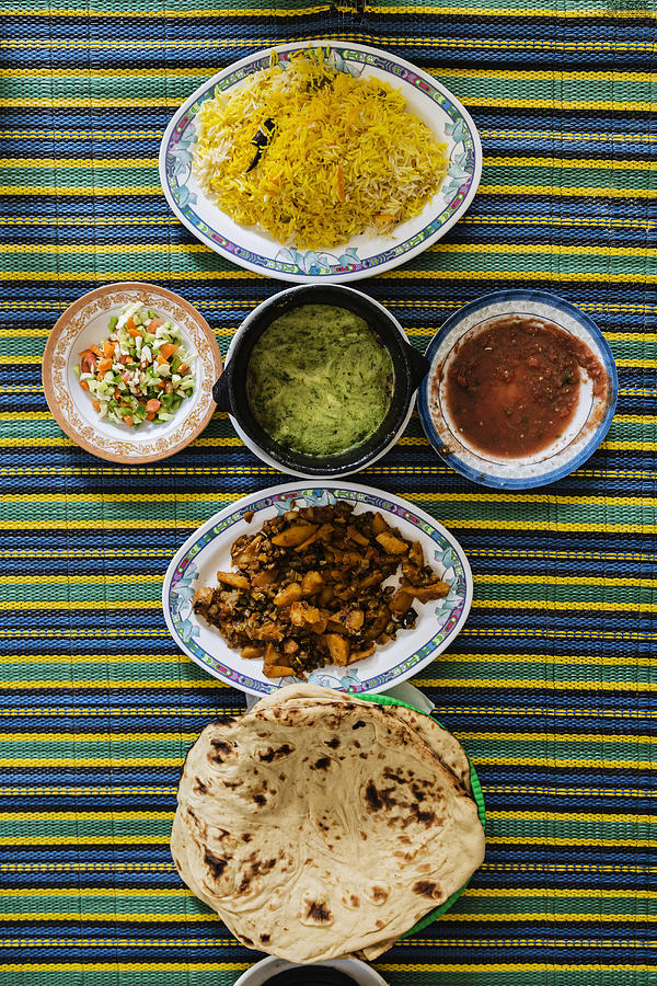 Plates of Yemeni food on striped tablecloth Photograph by Jeremy Woodhouse