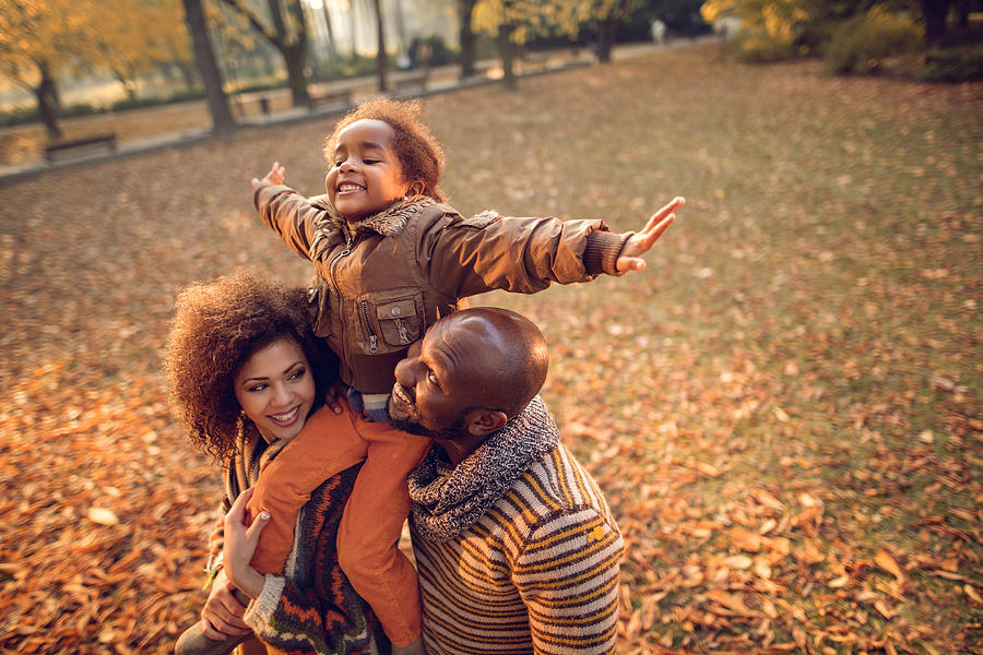 Playful African American little girl having fun with parents outdoors. Photograph by Skynesher