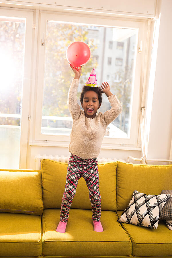 Playful black girl having fun on a party at home. Photograph by Skynesher