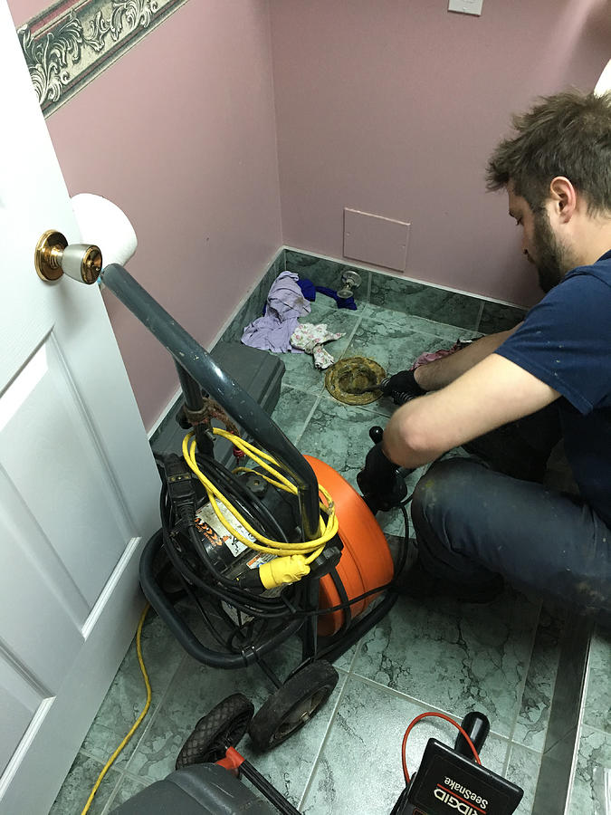 Plumber pushing a camera into toilet hole to find out where the sanitary drain is clogged Photograph by Marc Dufresne