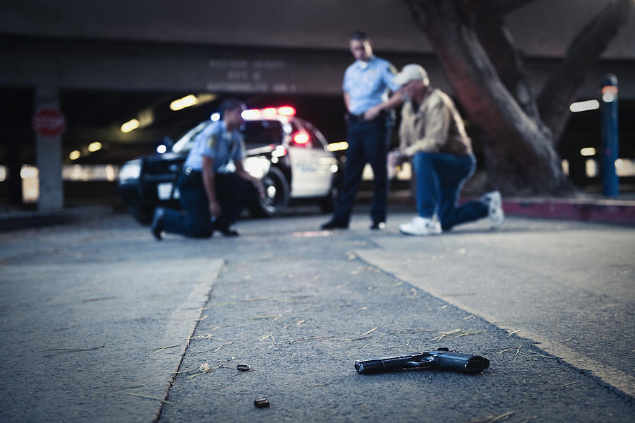 Police examining crime scene with gun on ground Photograph by Hill Street Studios