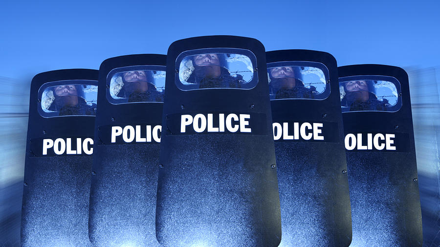 Policemen behind shields Photograph by Thinkstock Images