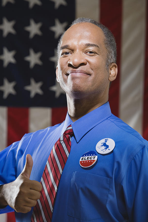 Politician with thumbs up by American flag Photograph by Thinkstock Images