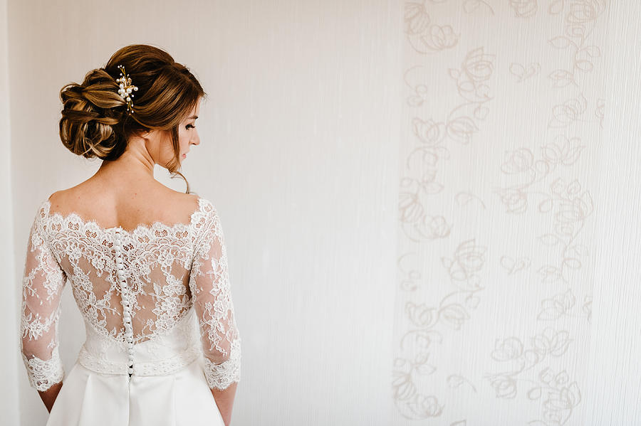 Portrait of a beautiful stylish bride with an elegant hairstyle view from the back. Wedding, people, fashion and beauty concept - bride in wedding dress. Back view. Photograph by Serhii Sobolevskyi