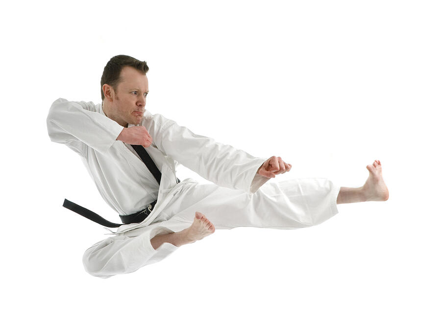 Portrait of a black belt man doing a high kick on white Photograph by Iainking