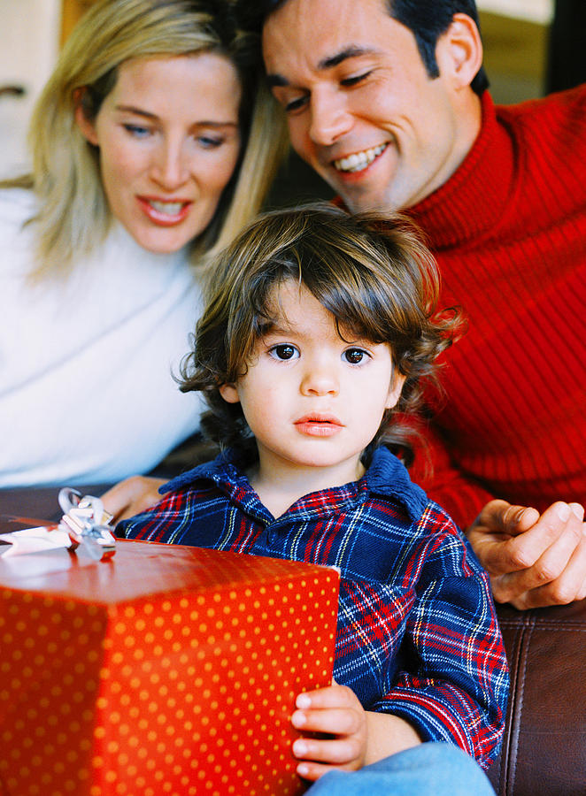 Portrait Of A Boy (4-6 Years) Holding A Present With His Parents Behind Him Photograph by Stockbyte