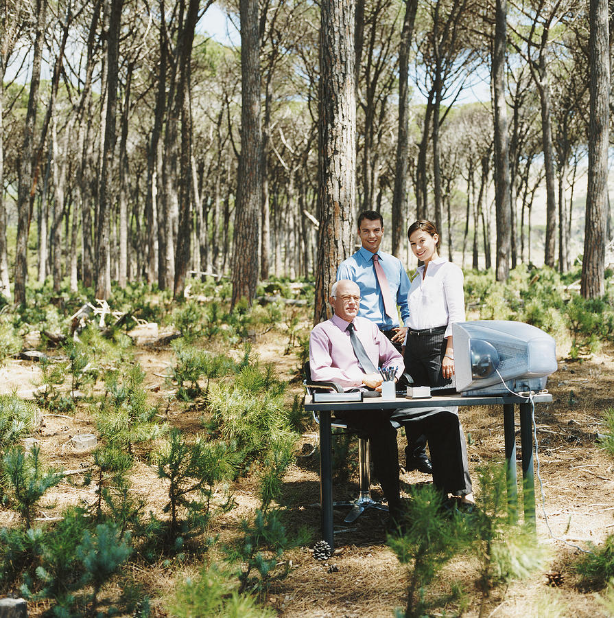 Portrait of a Businesswoman and Businessmen by a Desk in a Forest Photograph by Digital Vision.