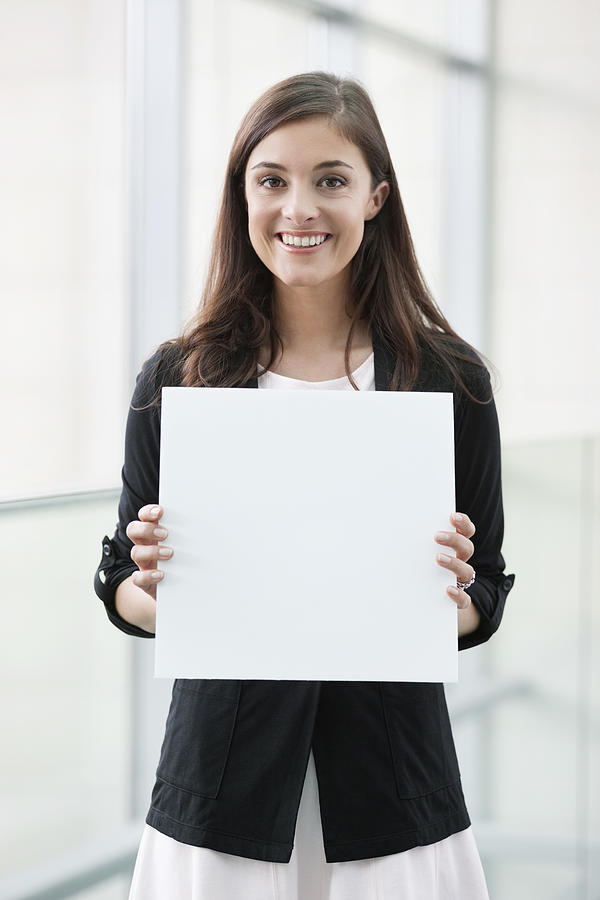 Portrait of a businesswoman holding a blank placard and smiling in an office Photograph by Fabrice LEROUGE