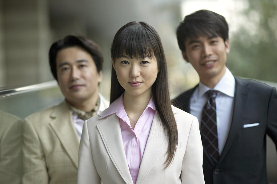 Portrait of a Businesswoman in Front of Two Businessmen Photograph by Digital Vision.