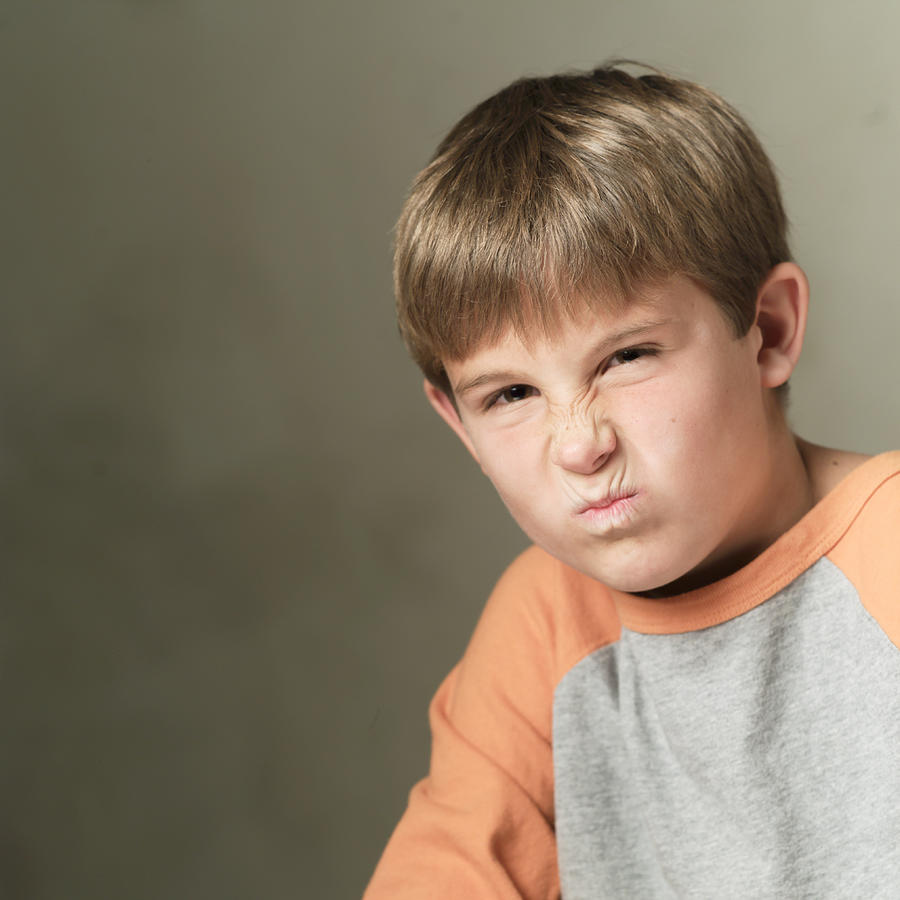 Portrait Of A Caucasian Boy In A Grey And Orange Shirt Grimaces And Frowns Into The Camera Photograph by Photodisc