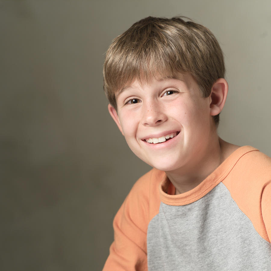 Portrait Of A Caucasian Boy In A Orange And Grey Shirt As He Smiles Brightly At The Camera Photograph by Photodisc