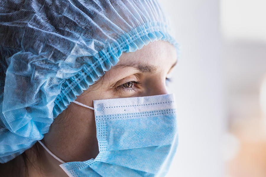 Portrait of a doctor woman in a medical mask and a protective cap. Photograph by Anton Petrus