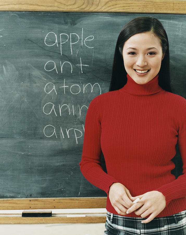 Portrait of a Female Thirtysomething Teacher Standing in Front of a Blackboard Photograph by Digital Vision.