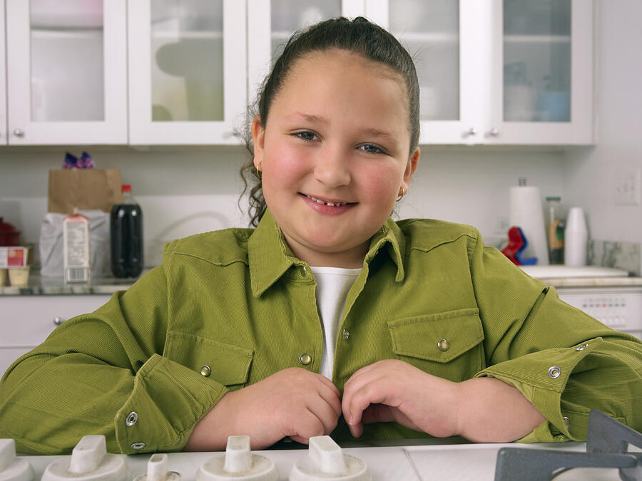 Portrait of a Girl in a Kitchen Wearing a Green Shirt Photograph by Digital Vision.