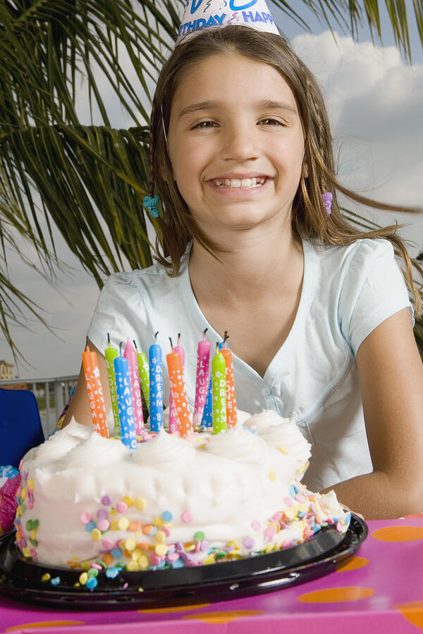 Portrait of a girl smiling in front of a birthday cake Photograph by Glowimages
