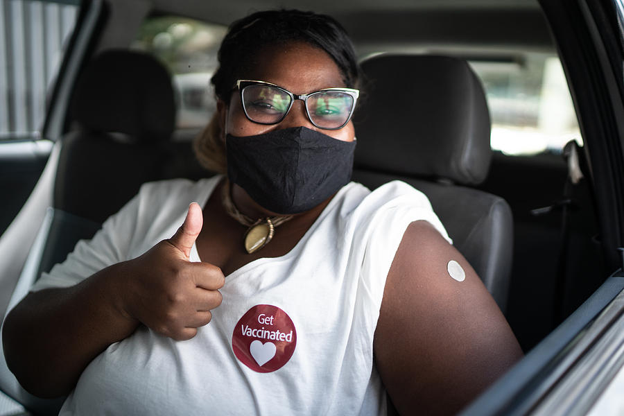 Portrait of a happy woman in a car with a get vaccinated sticker - wearing face mask Photograph by FG Trade