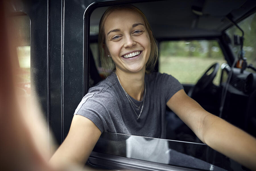 Portrait of a happy young woman in an off-road vehicle Photograph by Oliver Rossi