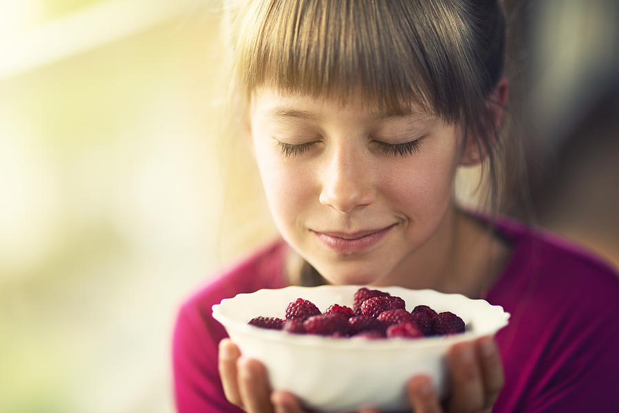Portrait of a little girl with raspberries. Photograph by Imgorthand