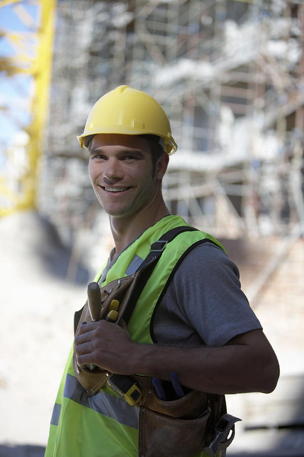 Portrait of a Male Builder Wearing a Hard Hat, Fluorescent Jacket and Tool Belt Photograph by Digital Vision.