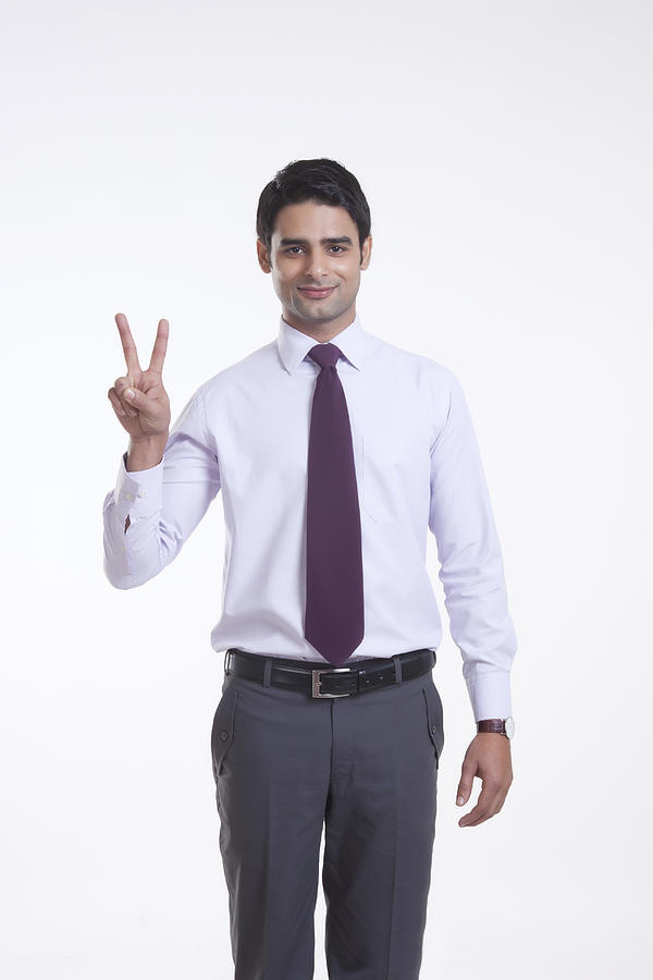 Portrait of a male executive giving peace sign Photograph by IndiaPix/IndiaPicture