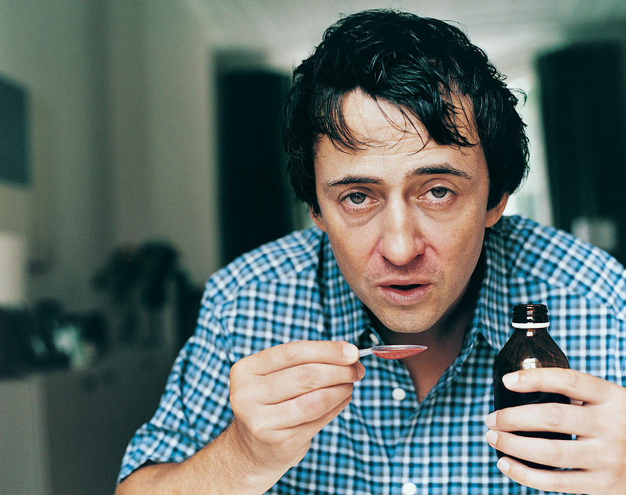 Portrait of a Man Taking Cough Medicine Photograph by Digital Vision.