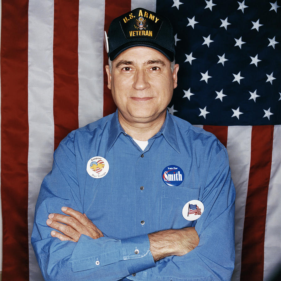 Portrait of a Mature Male Veteran Standing in Front of a Stars and Stripes Flag Wearing Election Badges Photograph by Digital Vision.
