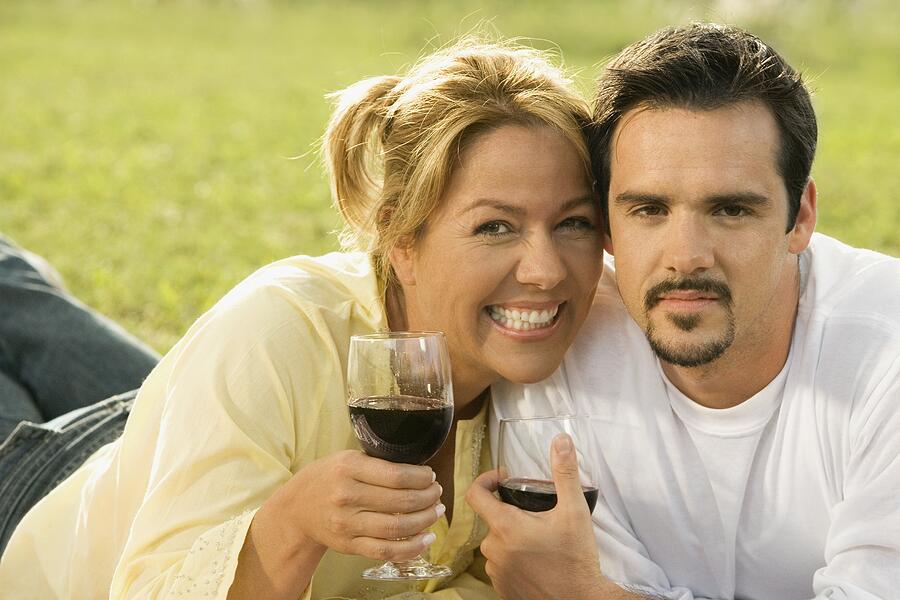 Portrait of a mature man and a young woman holding glasses of red wine Photograph by Glowimages