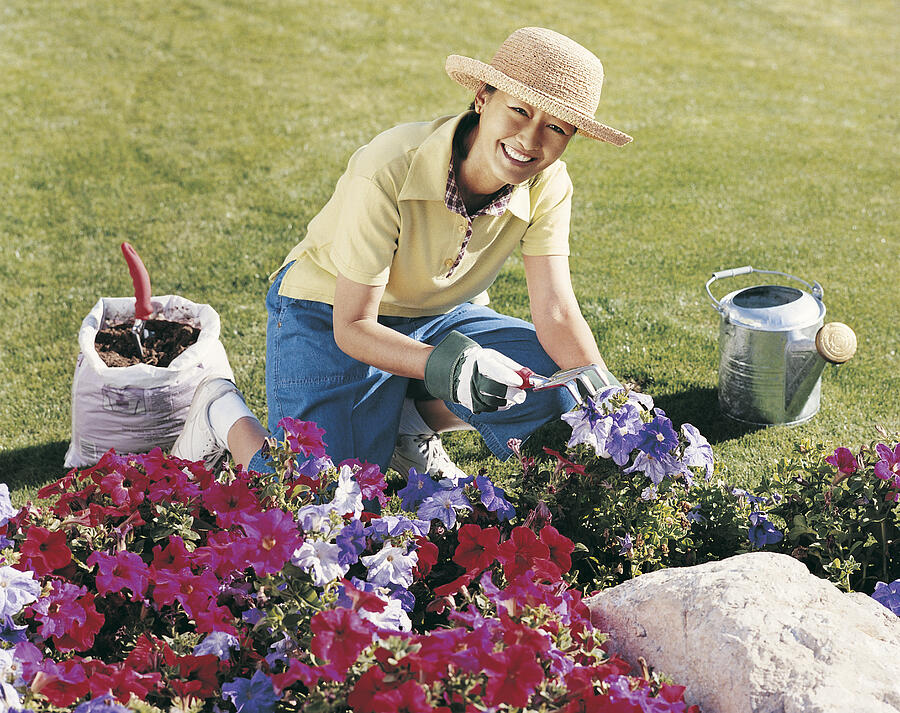Portrait of a Mature Woman Kneeling at a Flowerbed in Her Garden and Holding a Gardening Fork Photograph by Digital Vision.